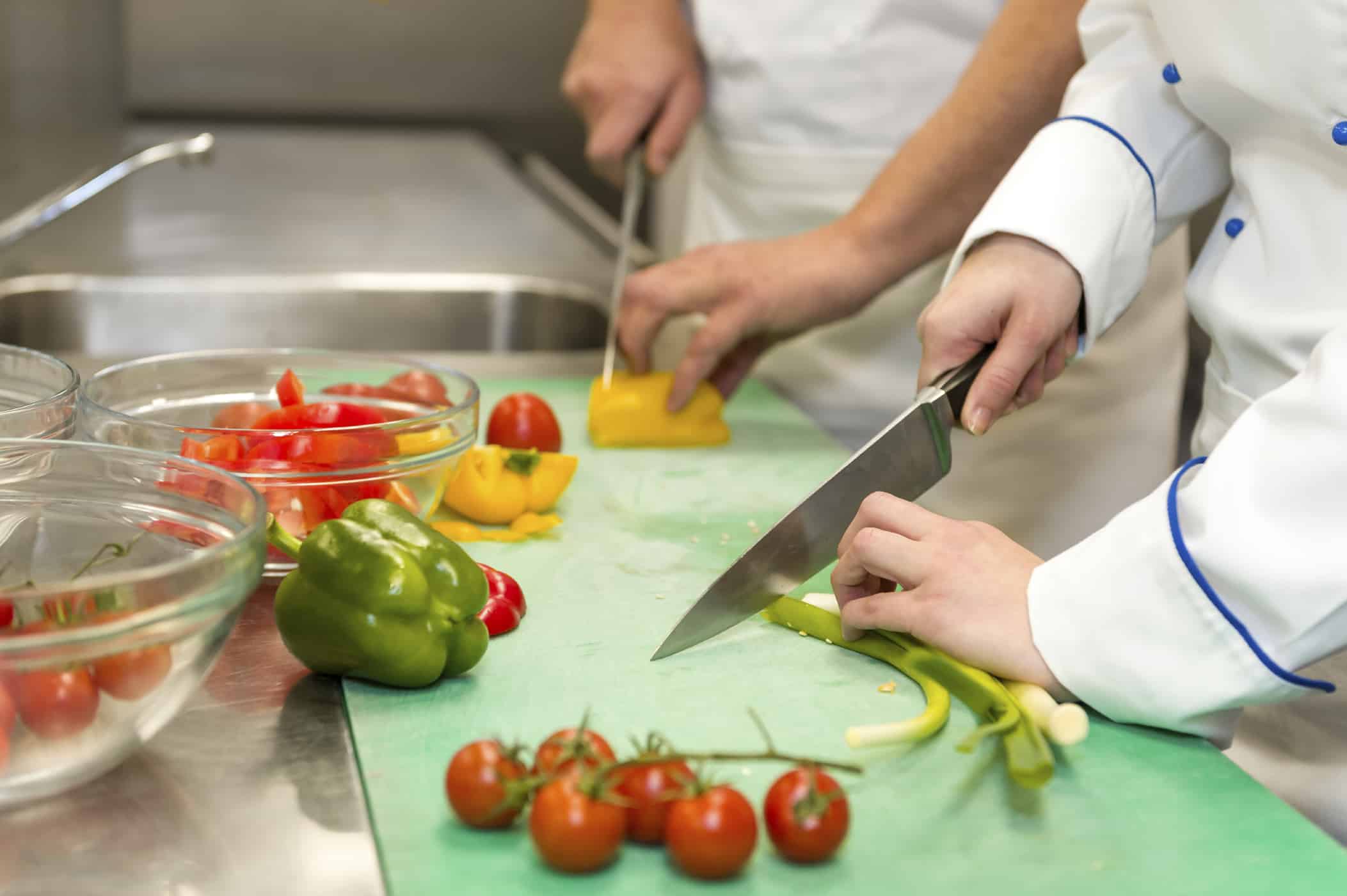 Two chefs cutting various vegetables