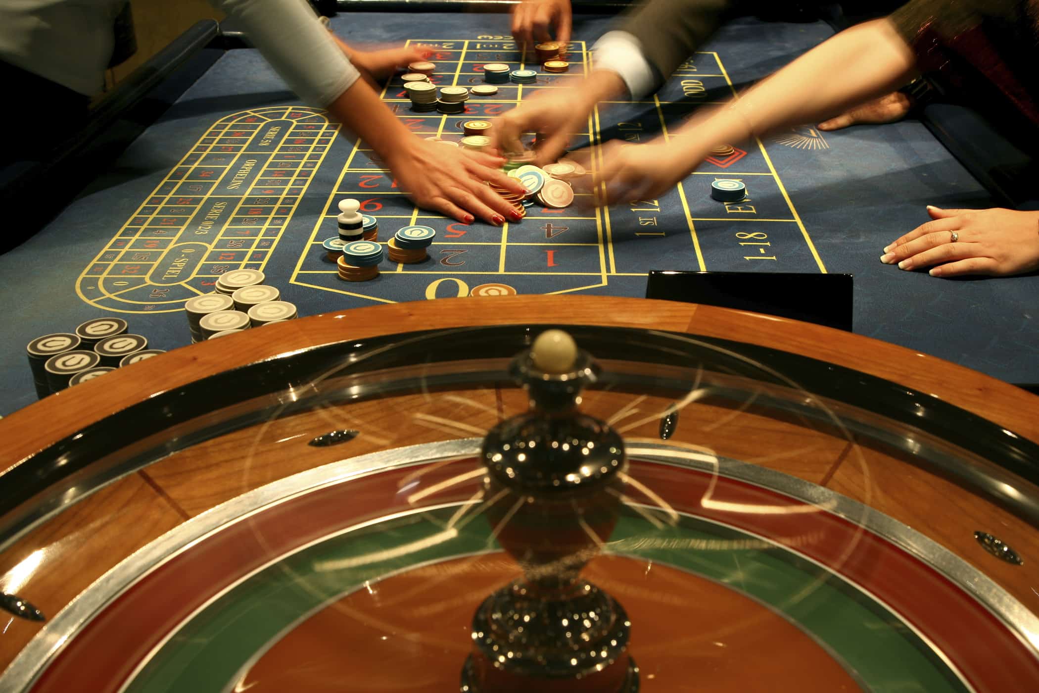 Close up of multiple sets of hands playing a casino game