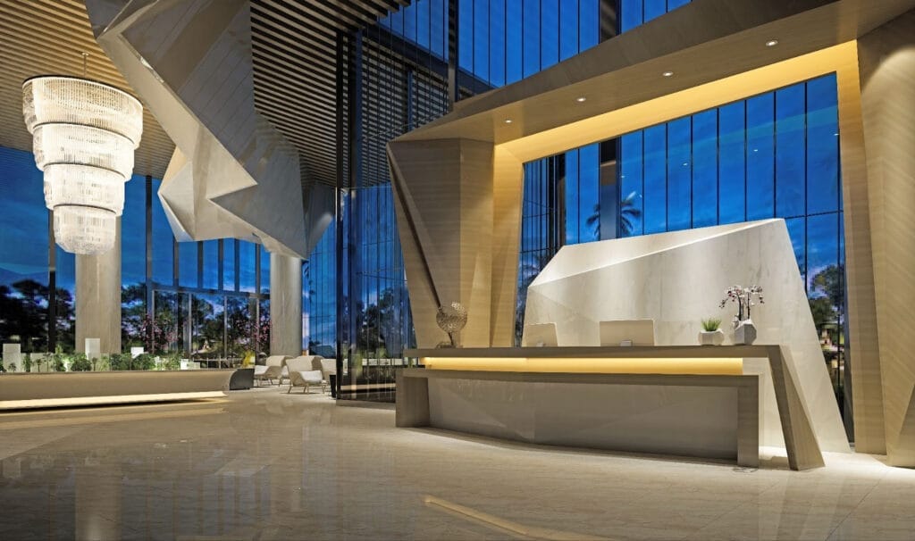 Wide-angle shot of a grand luxury hotel lobby with marble floors and chandeliers.