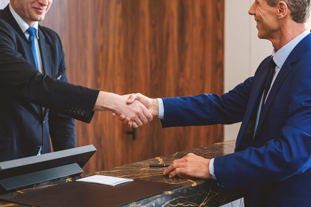 Hotel executive shaking hands with an operations manager, partnership imagery.