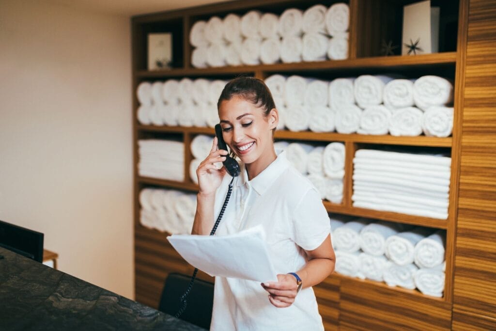 Hotel spa employee smiling and talking on the phone while holding a piece of paper.