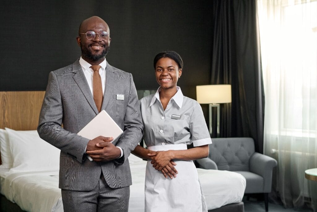 Two hotel employees smiling in a hotel room.