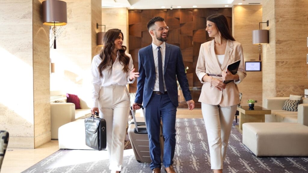 Three hotel guests are walking, talking, and smiling through the hotel lobby.  