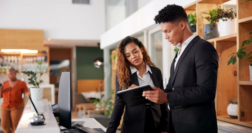 Two hotel employees speaking to each other at the front desk.